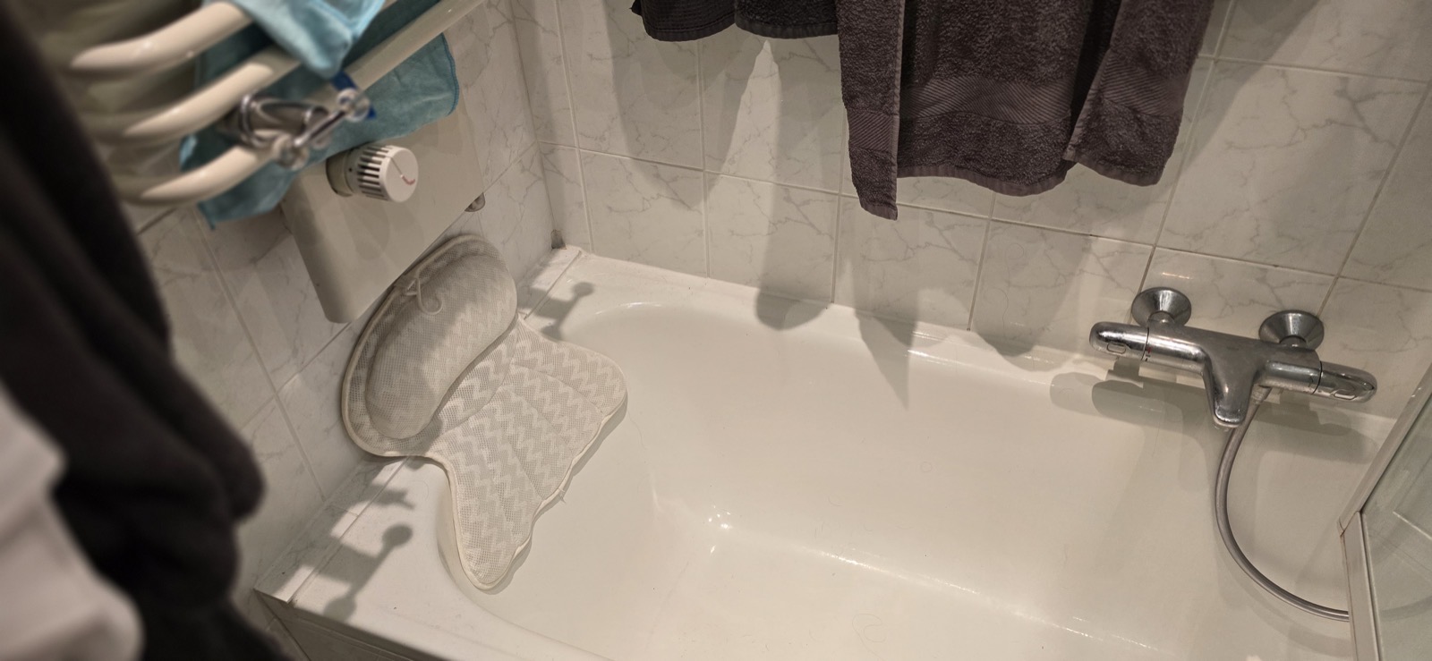 Alte Badewanne mit dunklen Marmorimitat-Fliesen und hängenden Handtüchern — Bielefelder Str. 25
