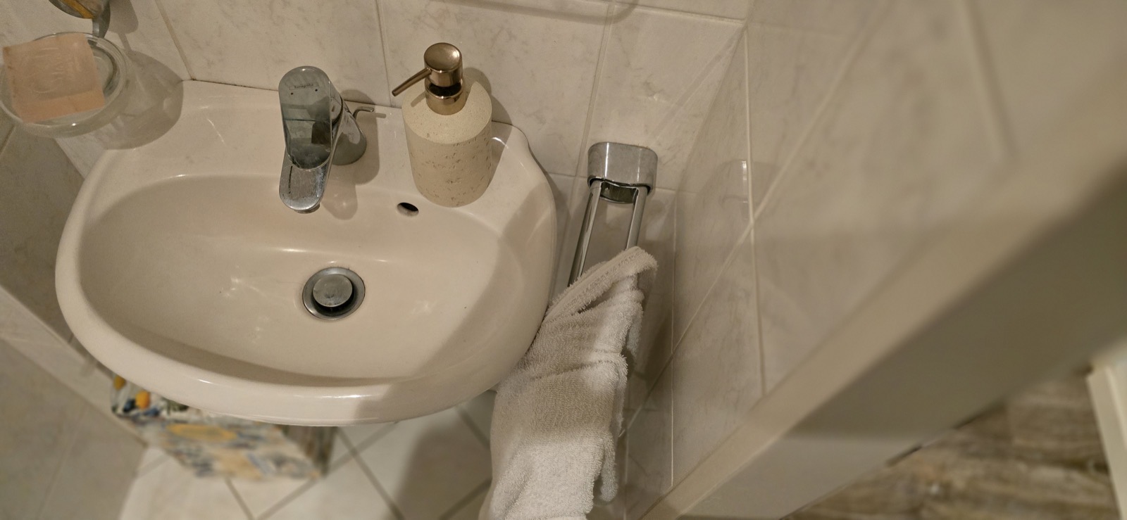 Kleines altes Wand­waschbecken mit Chrom­armatur und beigem Handtuch im Gäste-WC — Bielefelder Str. 25