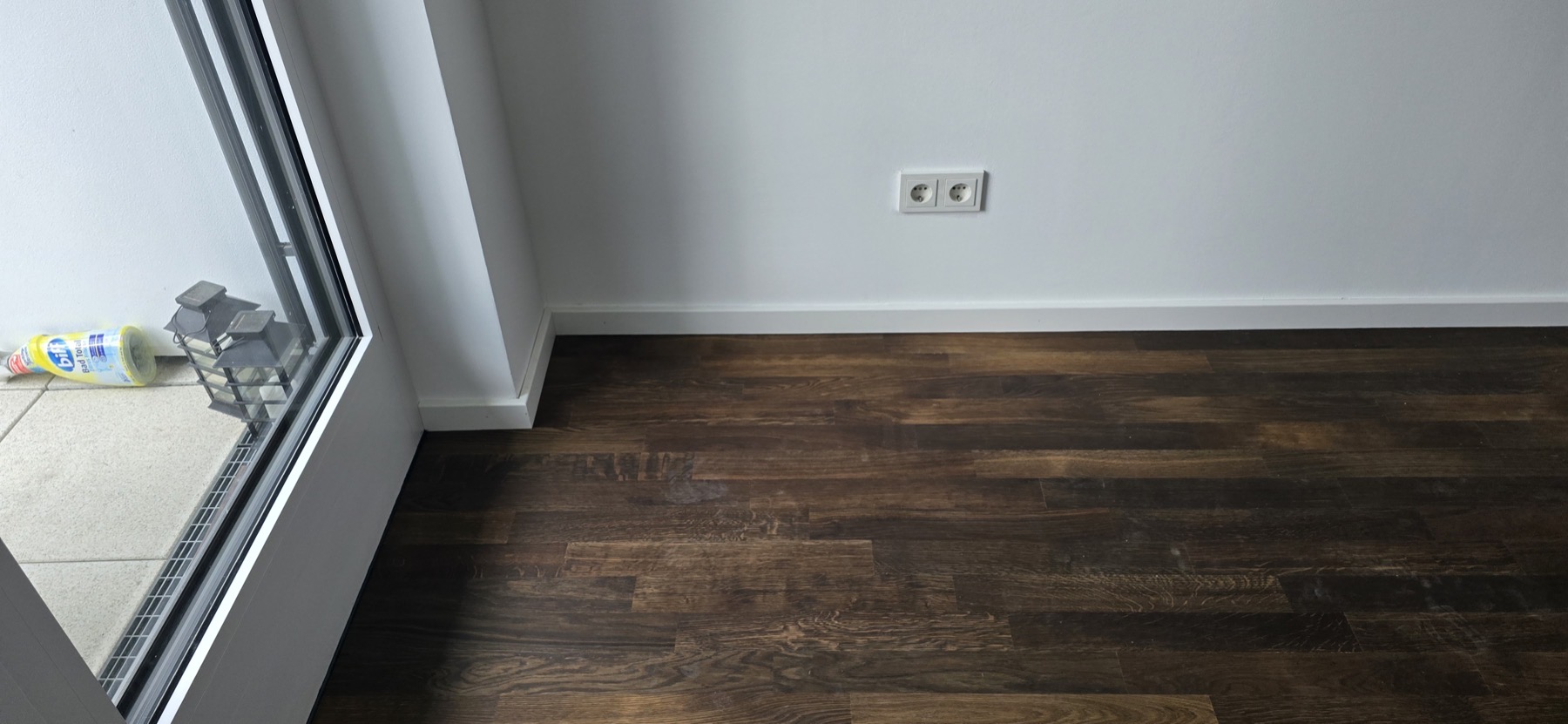 Fertig sanierter Wohnraum mit dunklem geöltem Parkettboden und Tageslicht von der Balkontür — Europaallee Wohnung H 07-07